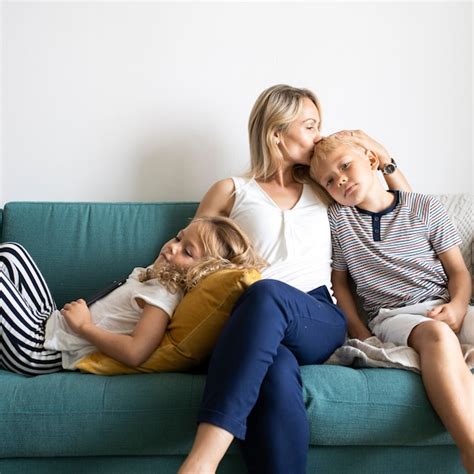 Maman Blonde Embrasse La Tête De Son Fils Et Se Détend Avec Sa Fille Sur Le Canapé Photo Gratuite