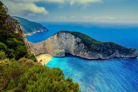 Green And Brown Mountain Beside Body Of Water Landscape Beach Sea