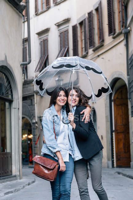 Lesbian Couple Standing Together In Street Holding Umbrella Looking At Camera Smiling Florence