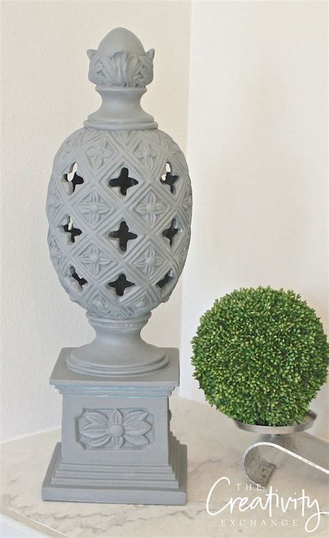 A White Vase Sitting On Top Of A Table Next To A Green Ball