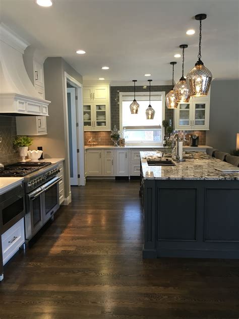Installing hardwood flooring in a kitchen in a kitchen, you want to make sure that you purchase a very dense, durable hardwood, and stay away from softwood floors that will be more prone to water. White Cabinets, Granite Island, dark wood floor, gray ...