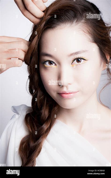 Portrait Of Young Smiling Korean Woman With Long Wavy Hair Touched By