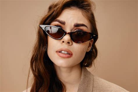 Portrait Of Beautiful Brunette Woman Wearing Glasses On Beige