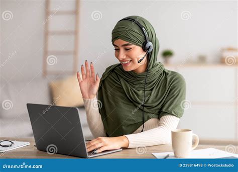 Cheerful Young Arab Woman In Hijab And Headphones Making Video Call On