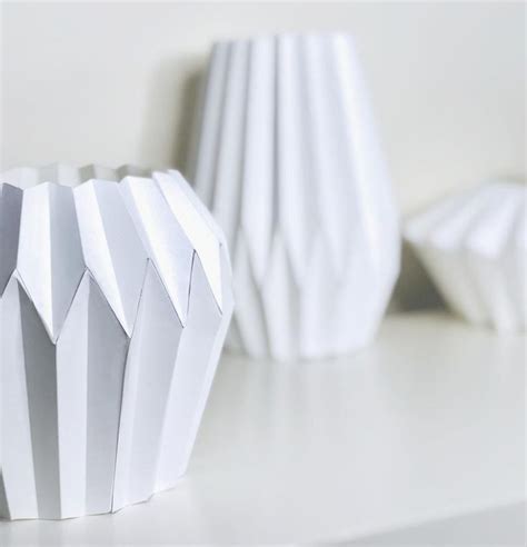 Three White Vases Sitting On Top Of A Table Next To Each Other And One