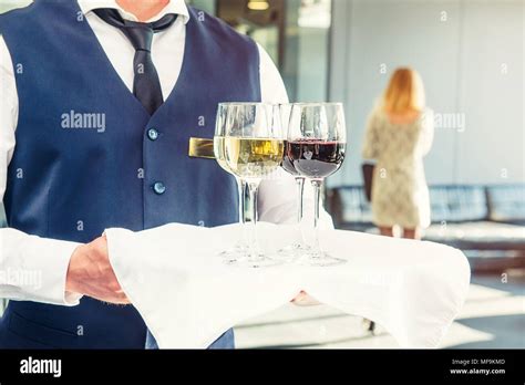 Professional Waiter In Uniform Holding A Tray With Glasses Of Vine At