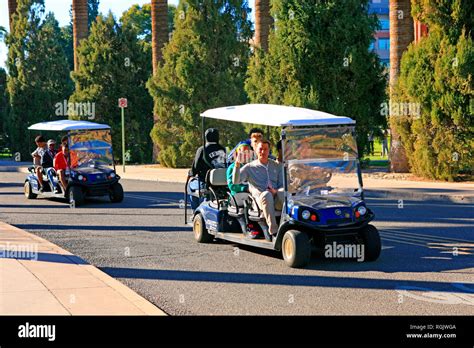 Guest College Football Team Members Getting A Guided Tour On Golf Carts