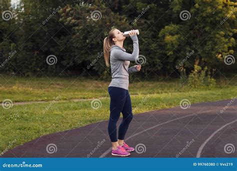 Portrait Of Pretty Sporty Woman Drinking In The Park Stock Photo