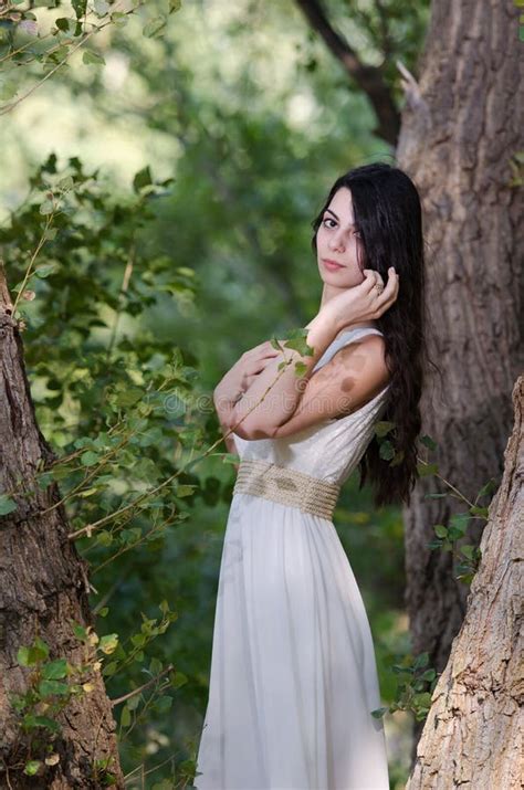 Woman With Long Hair Wearing White Dress Pose In The Forest Stock