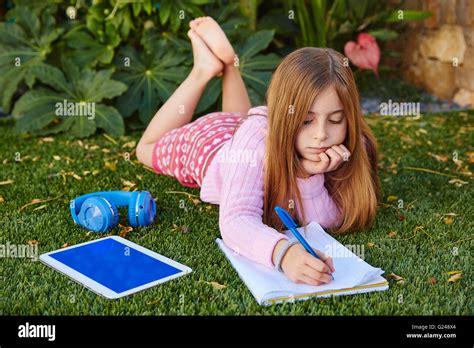blonde junge mädchen hausaufgaben liegen auf rasen rasen schreiben notebook stockfotografie alamy
