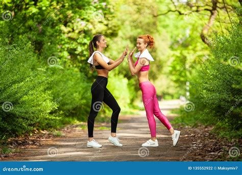 Two Women Exercising In The Park Young Beautiful Woman Doing Exercises