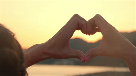 Hands Forming A Heart Shape With Sunset Silhouette Ocean Sun Shining
