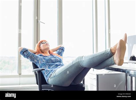 Full Length Of Businesswoman Relaxing With Feet Up At Desk In Creative