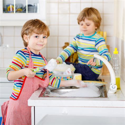 Two Funny Little Boy Friends Washing Dishes In Domestic Kitchen Stock