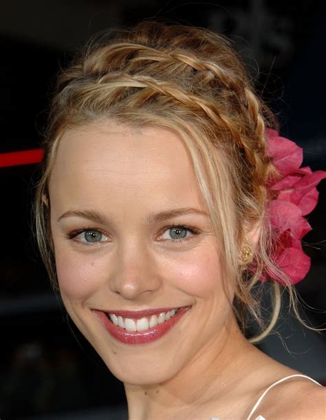 A Woman With A Flower In Her Hair Smiling At The Camera While Wearing A