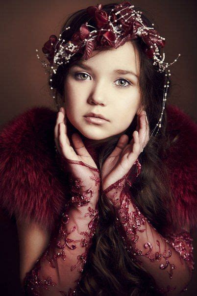 A Woman With Long Hair Wearing A Red Dress And Fur Stole Holding Her Hands To Her Face