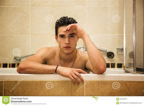 Красивый молодой человек в ванне дома имея ванну Стоковое Фото изображение насчитывающей