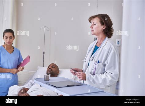 Doctors Diagnosing Patient Lying In Hospital Bed Stock Photo Alamy