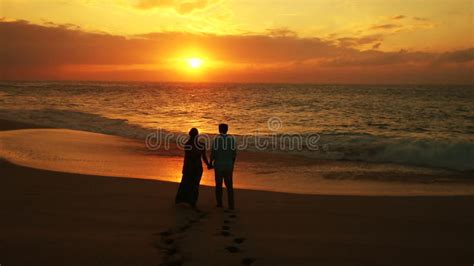 Silhouette Of Couple Walking On Beach At Sunset Holding Hands Happy Man And Girl On Seashore In