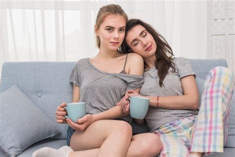 Junge Lesbische Paare Die In Der Hand Auf Dem Sofa Hält Tasse Kaffee