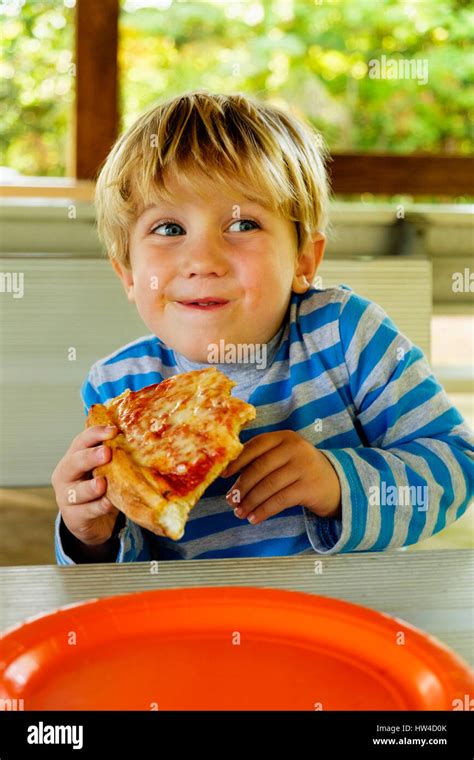 Playful Caucasian Boy Eating Slice Of Pizza Stock Photo Alamy