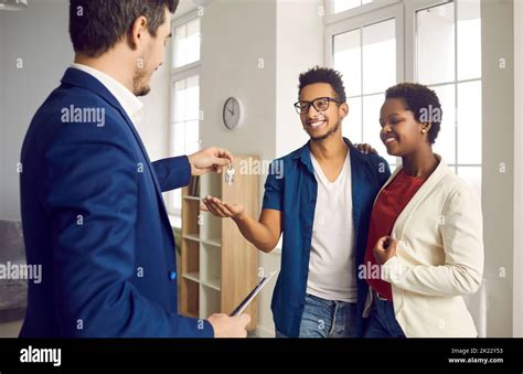 During Meeting With Happy Young Married Couple Realtor Gives Them Keys