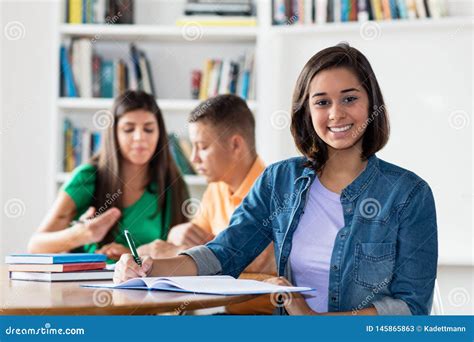 Smart Spanish Female Student With Group Of Learning Students Stock