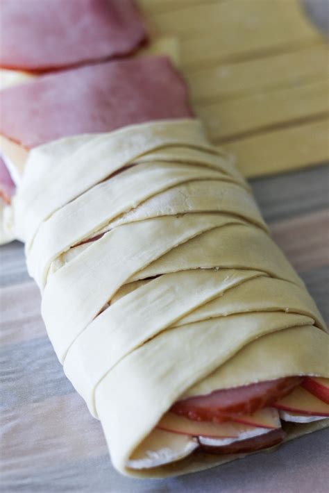 Freshly baked salty braided bread loaf on a baking sheet. Braided Ham & Brie Stuffed Pastry