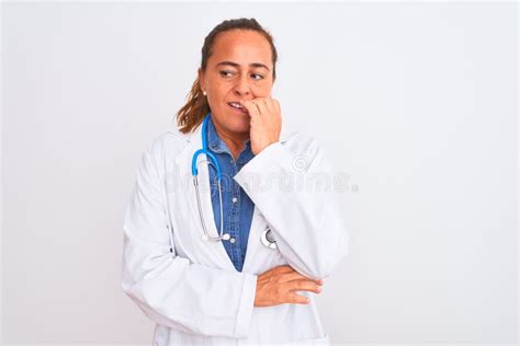 middle age mature doctor woman wearing stethoscope over background looking stressed and nervous