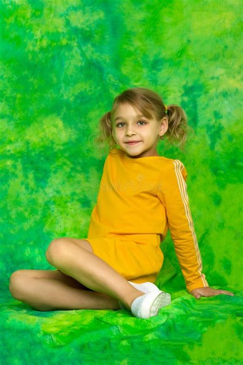 A Cute Little Girl Is Sitting In The Studio On A Bright Green