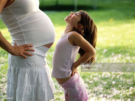 Girl Thrusting Stomach At Pregnant Mother Side View High Res Stock