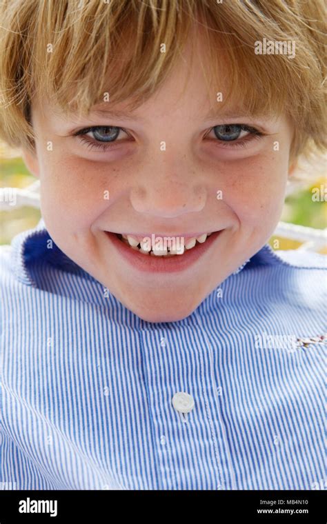 Head And Shoulders Portrait Of Smiling Boy With Blonde Hair And Blue