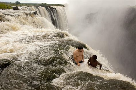 Two Guys Sitting Near The Edge Of The Devils Pool Victoria Falls Zambia