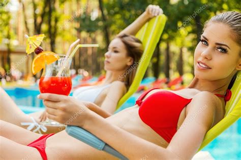Women In Bikini Drinking Cocktails Near The Pool Stock Photo