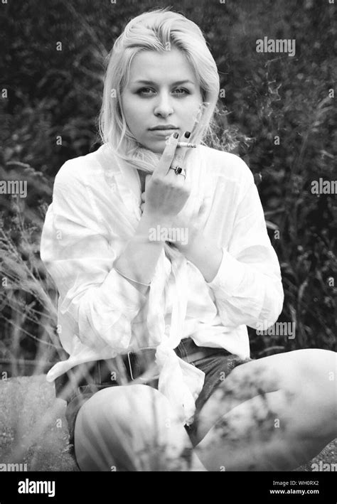 Close Up Portrait Of Young Woman Smoking Cigarette On Field Stock Photo