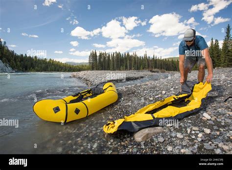 Paddler rolls out inflatable packraft before a day of paddling Stock