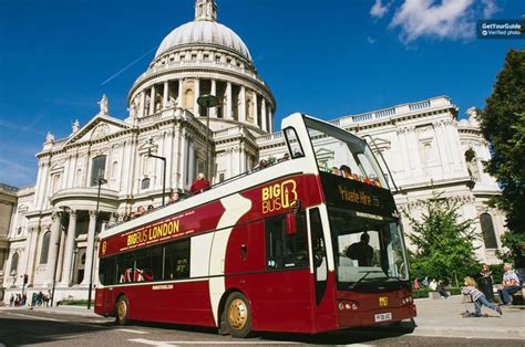 a red and white double decker bus parked in front of a building with a dome