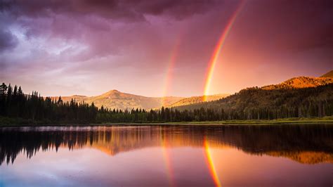 Green Trees Covered Mountain With Rainbow Reflection On