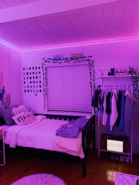 A Bedroom With Purple Lighting And Clothes Hanging On The Rack In Front