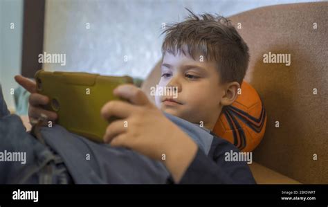 Preschooler Using Mobile Phone At Home Caucasian Boy Looks At Photos