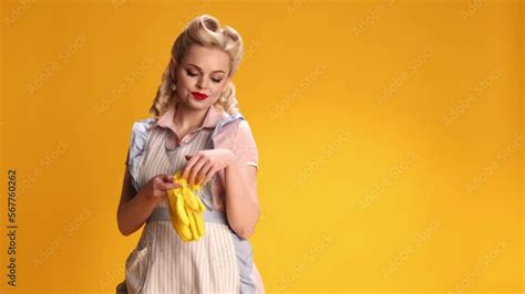 Beautiful Stylish Girl Housewife In Retro Apron Putting On Rubber Gloves For Cleaning Over