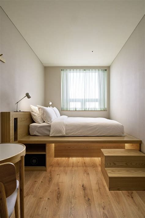 A Bed Sitting On Top Of A Wooden Platform Next To A Window In A Bedroom
