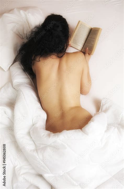 Woman With Naked Back Lying In Bed And Reading A Book Stock Photo