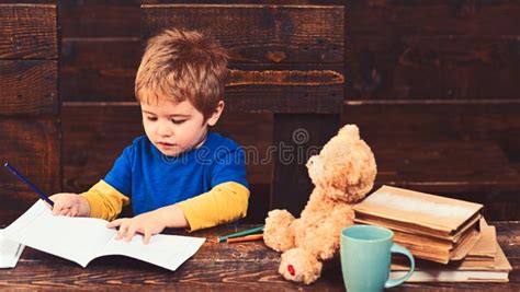 Concentrated Kid Writing In Copybook Preschool Boy Sitting At Desk