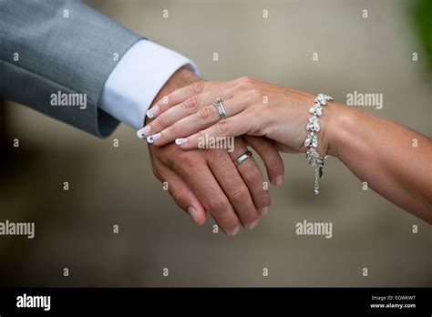 A Recently Married Couple Hold Hands Showing Off Their Rings Just