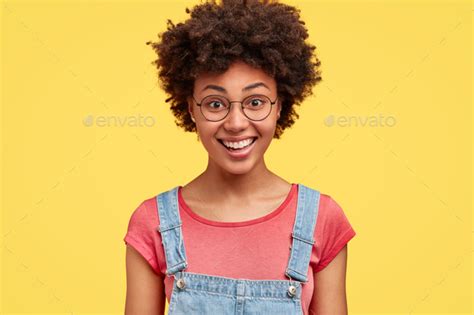 Happy Dark Skinned Female With Afro Hairstyle Has Pleased Expression