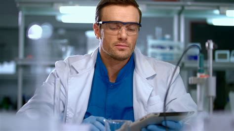 Young scientist using tablet pc in laboratory. Scientist searching data ...