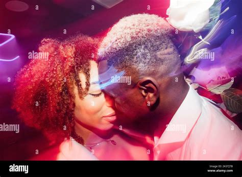 Drunk African American Couple Kissing And Dancing Under Bright Neon Light While Having Fun