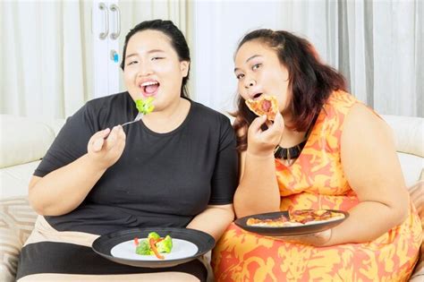 Premium Photo Two Happy Fat Women Eating Salad And Pizza Together