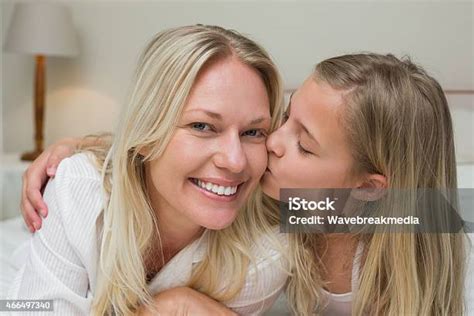 Girl Kissing Mother On Cheek In Bed Stock Photo Download Image Now